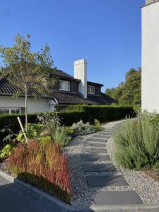 Aménagement paysager contemporain avec allée en pas japonais sur gravier et plantations structurées