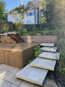 Aménagement paysager en terrasses avec marches en pierre et plateforme en bois