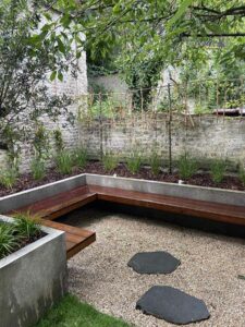 Jardin urbain avec assise en bois et sol en gravier clair