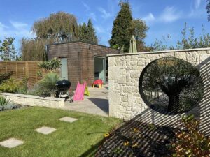 Jardin moderne avec mur en pierre ajouré et abri de jardin en bois