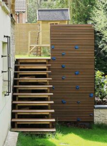 Escalier en bois avec paroi d’escalade intégrée menant à une cabane de jardin