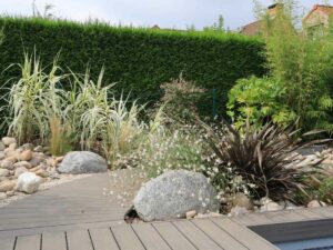 Aménagement paysager combinant galets, plantes ornementales et terrasse bois
