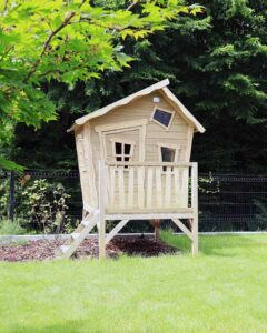 Cabane en bois pour enfants sur pilotis installée dans un jardin paysager