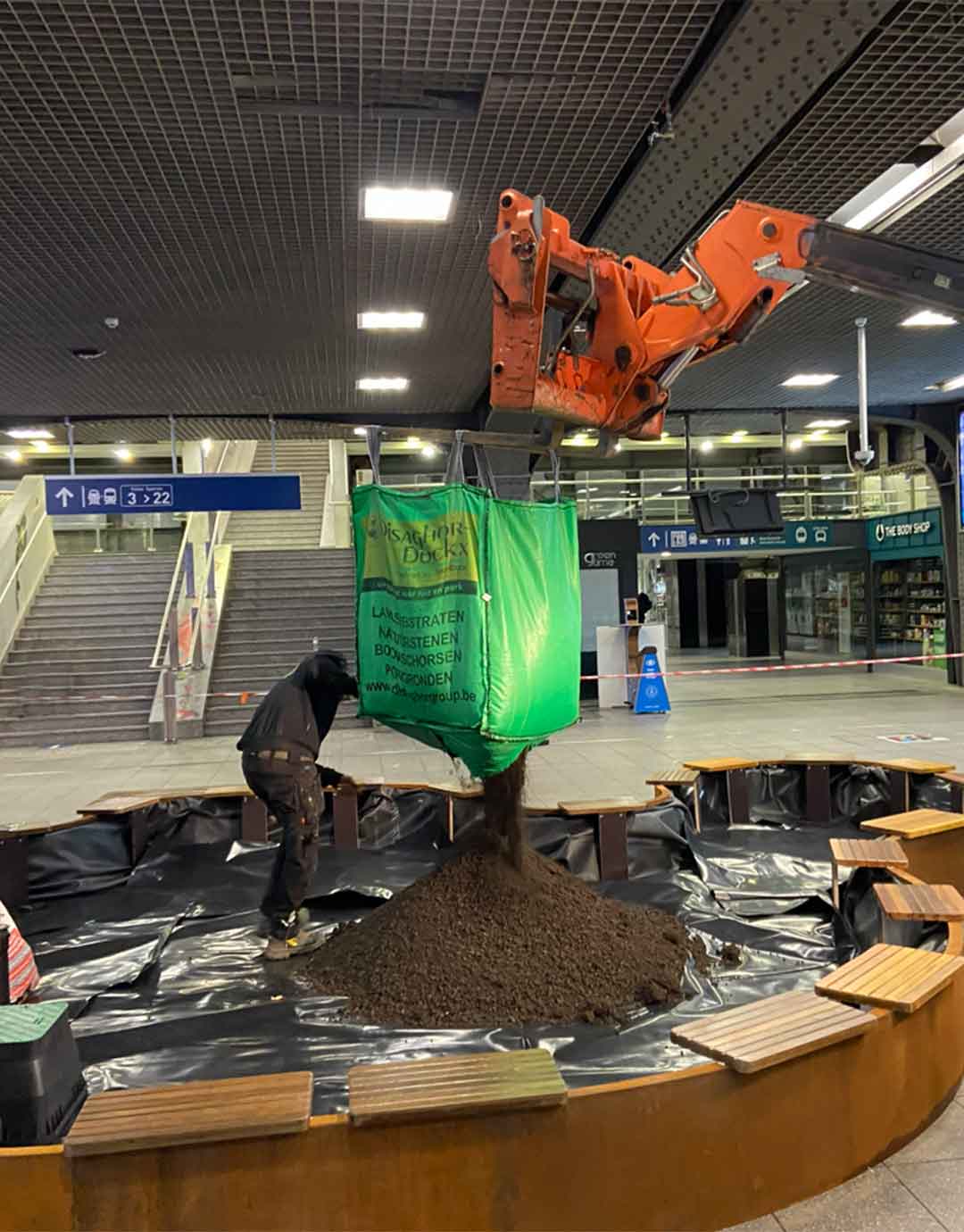 Ouvriers déposant du substrat dans un grand bac de plantation intérieur