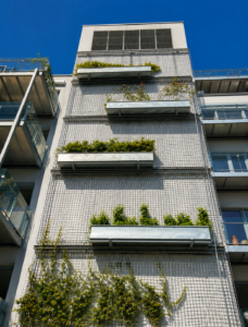 Façade d’immeuble moderne avec jardinières végétalisées et plantes grimpantes en milieu urbain.